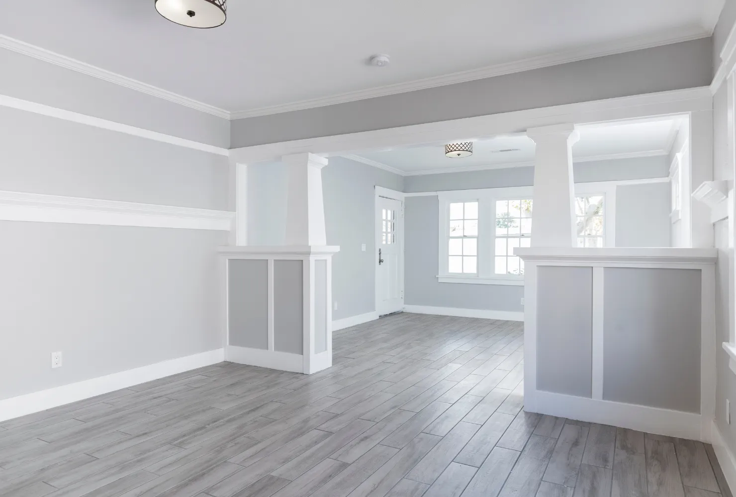 Open concept residential interior painting with soft gray walls, white columns, and clean modern trim