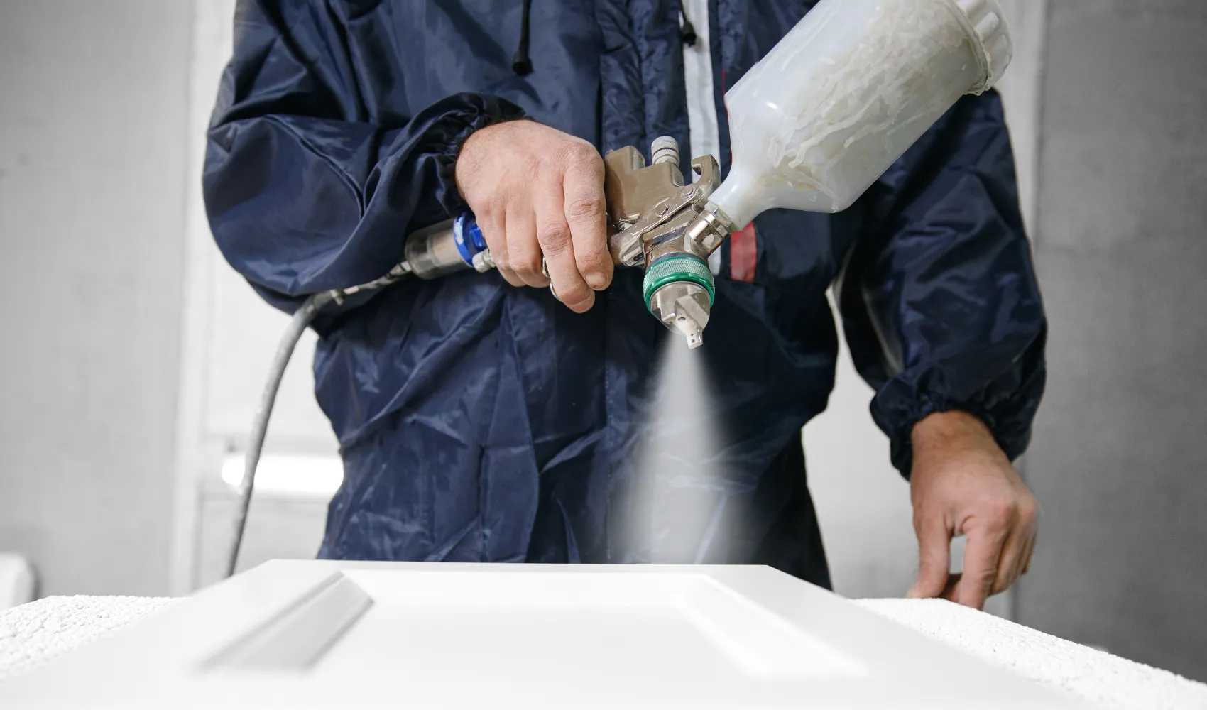 Close-up of expert cabinet painter spray painting kitchen cabinets for a flawless factory-quality finish in Los Angeles.