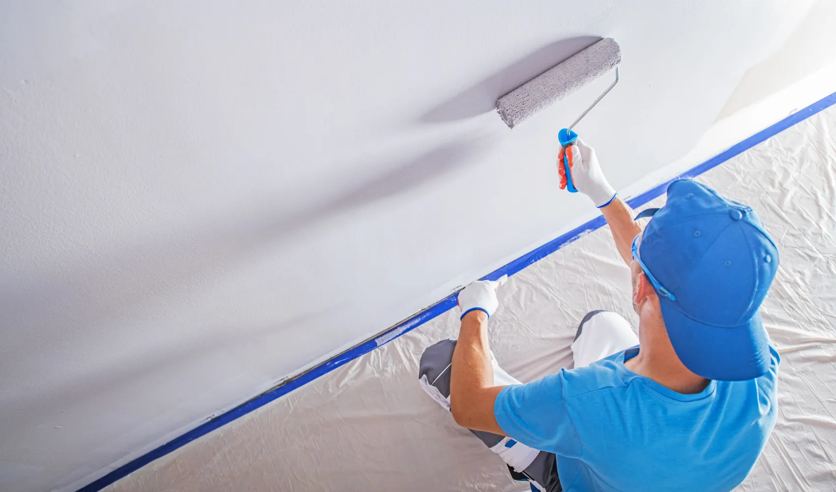 Residential interior painting service using roller to apply smooth, even wall paint finish